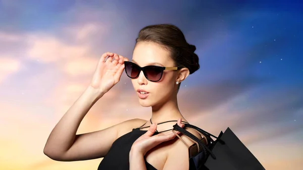 Щаслива жінка в чорних сонцезахисних окулярах з сумками — стокове фото