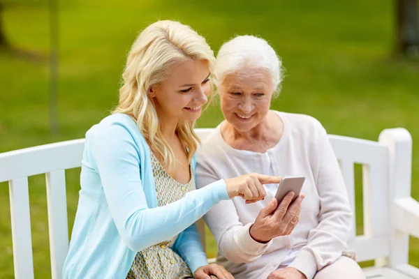 Dotter och senior mor med smartphone på park — Stockfoto