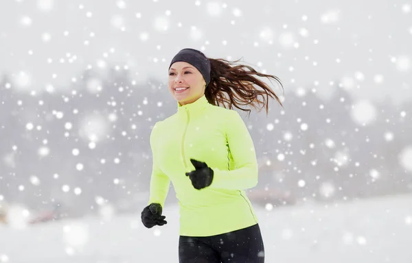 Lycklig kvinna löper längs snö täckta vinterväg — Stockfoto