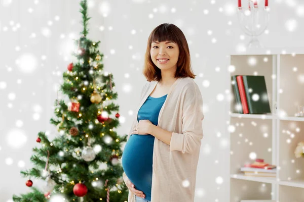Щаслива вагітна жінка на ялинці вдома — стокове фото