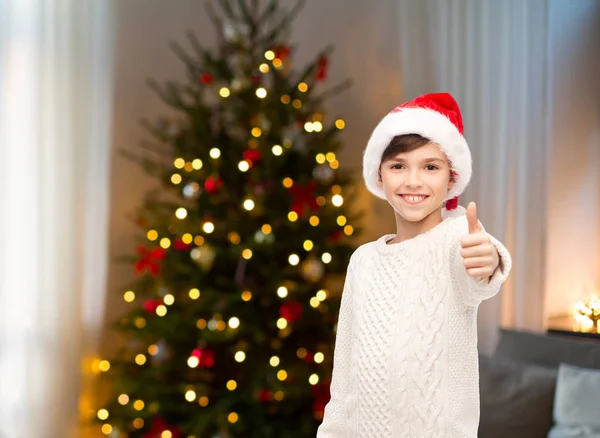 Lycklig pojke i santa hatt visar tummen — Stockfoto
