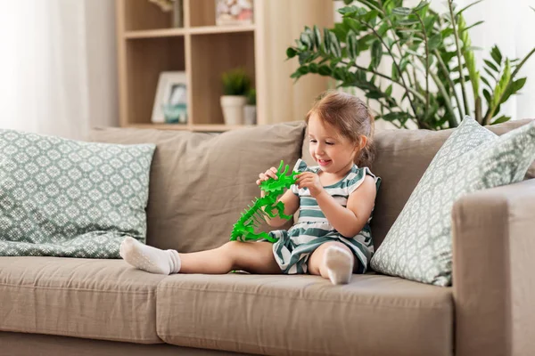 Menina feliz brincando com dinossauro brinquedo em casa — Fotografia de Stock
