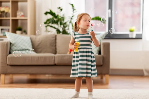 Liten flicka blåser såpbubblor hemma — Stockfoto