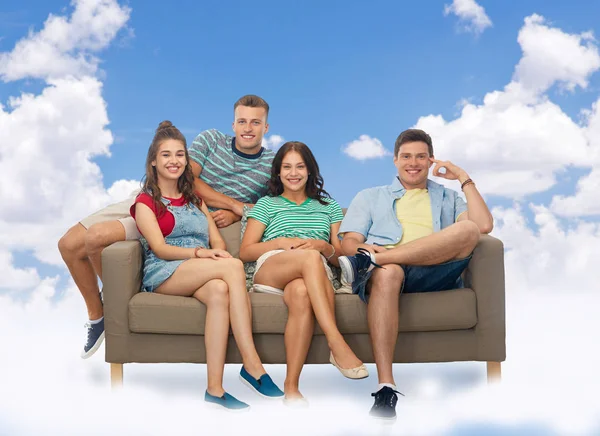 Друзья сидят на диване над небом и облаками — стоковое фото