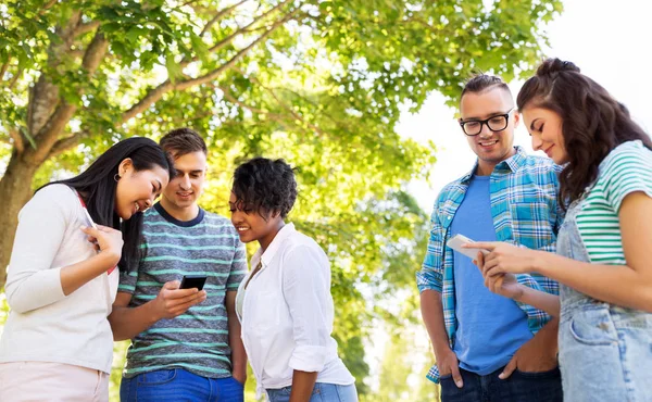 Amici felici con gli smartphone al parco estivo — Foto Stock