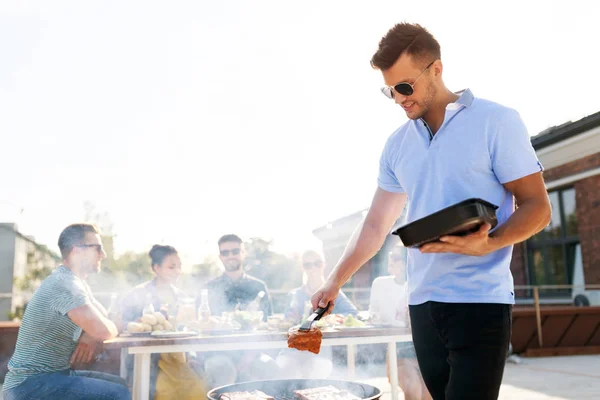 Man cooking meat on bbq at rooftop party — Stock Photo, Image