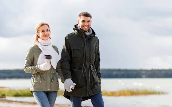 Casal com tumbler andando ao longo da praia de outono — Fotografia de Stock