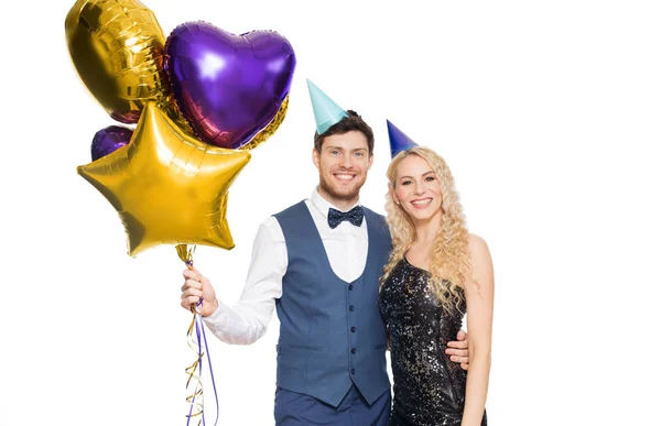 Feliz pareja con gorras de fiesta y globos — Foto de Stock