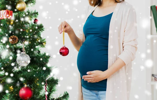 Terhes nő díszítő karácsonyfa — Stock Fotó