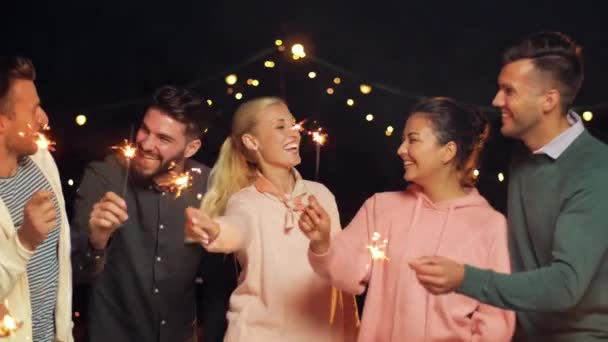 Счастливые друзья с искрящимися на вечеринке на крыше — стоковое видео