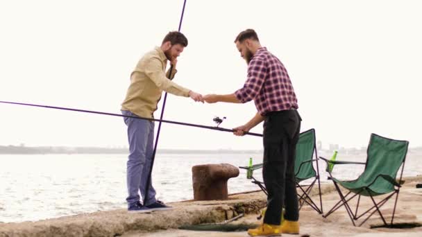 Amigos felices ajustando cañas de pescar en el muelle — Vídeos de Stock