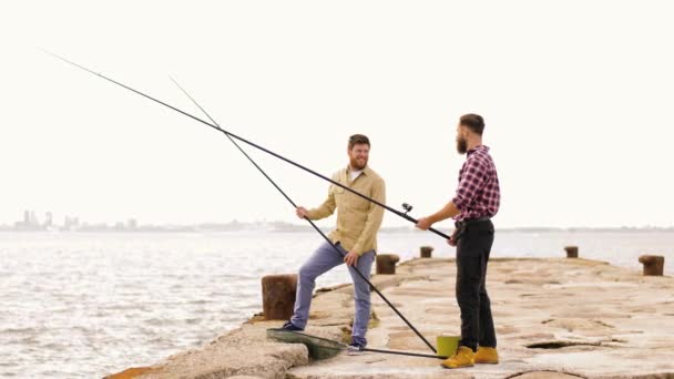 Šťastní přátelé s rybářskými pruty na molu — Stock video