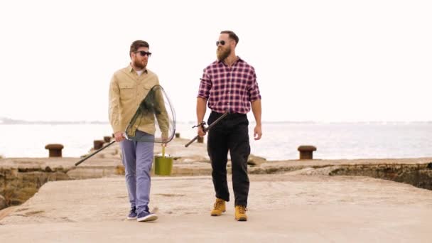Amigos felices con cañas de pescar caminando a lo largo del muelle — Vídeo de stock