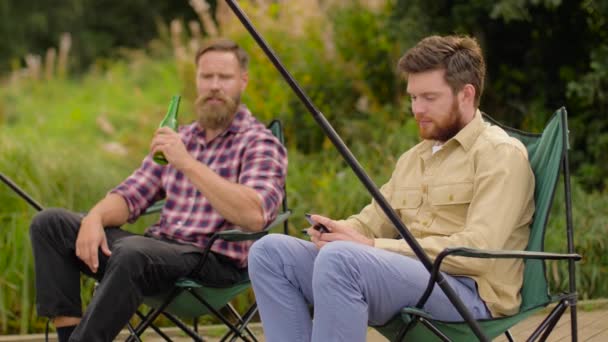 Vrienden met smartphone vissen en bier drinken — Stockvideo