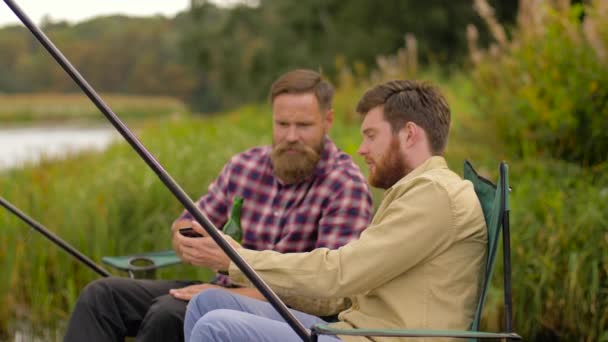 Amici con smartphone e birra pesca sul lago — Video Stock