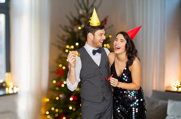 Casal com sopradores de festa se divertindo no Natal — Fotografia de Stock