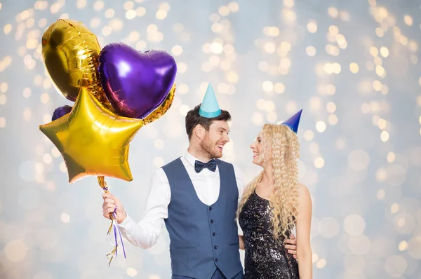 Ευτυχισμένο ζευγάρι στο κόμμα καπέλα με μπαλόνια — Φωτογραφία Αρχείου