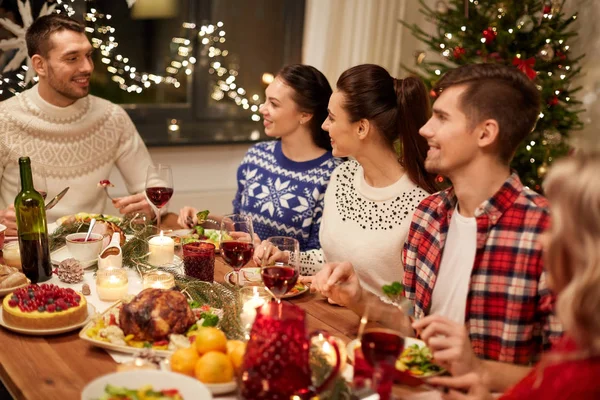 Glada vänner som äter julmiddag hemma — Stockfoto