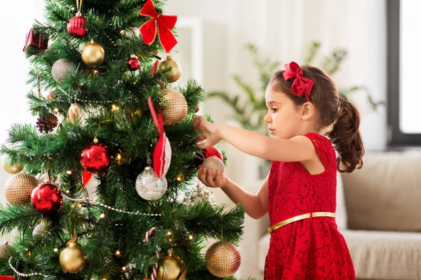 Kleines Mädchen schmückt Weihnachtsbaum zu Hause — Stockfoto