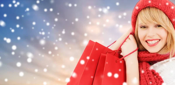 Mulher com sacos de compras vermelhas sobre fundo de neve — Fotografia de Stock