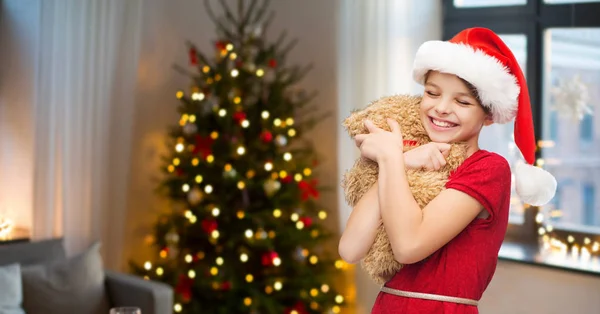 Meisje in kerstmuts met teddybeer op Kerstmis — Stockfoto