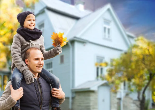 Vater und Sohn mit Herbst-Ahornblättern über Haus — Stockfoto