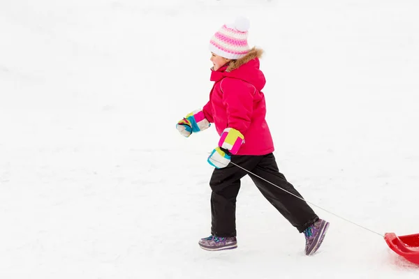 Bambina con slitte sulla collina di neve in inverno — Foto Stock