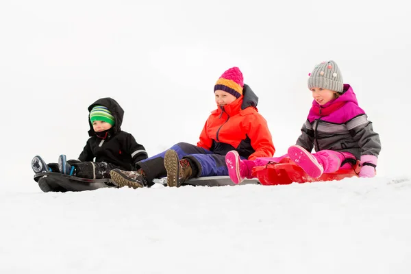 Crianças pequenas felizes que deslizam em trenós no inverno — Fotografia de Stock