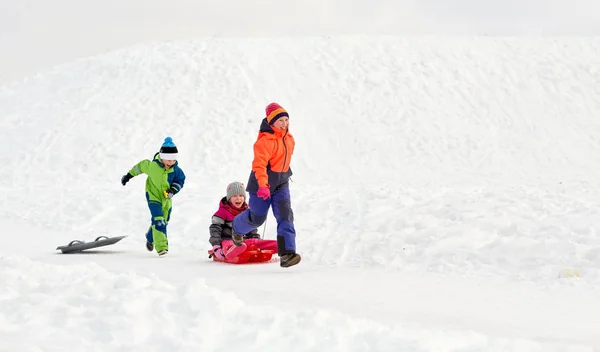 Glückliche Kinder mit Schlitten, die im Winter draußen Spaß haben — Stockfoto