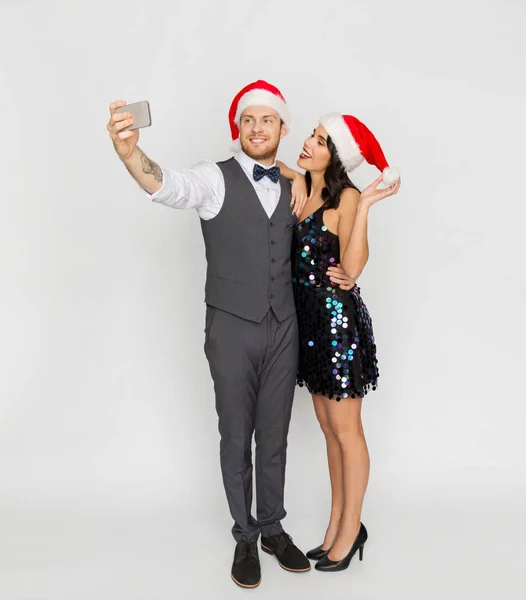 Coppia in cappelli di Babbo Natale facendo selfie a Natale Immagine Stock
