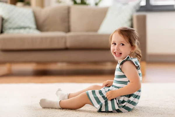 Szczęśliwe dziecko dziewczyna siedzi na podłodze w domu — Zdjęcie stockowe
