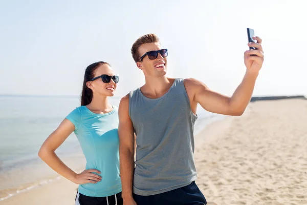 Пара делает селфи на смартфоне на пляже — стоковое фото
