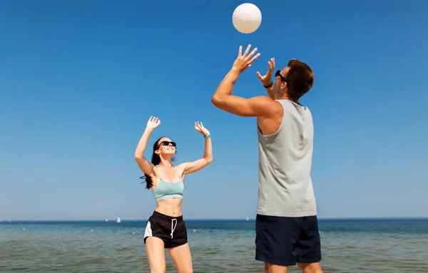Счастливая пара играет в волейбол на летнем пляже — стоковое фото