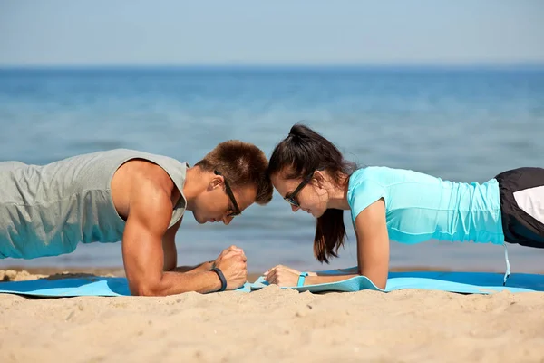 Couple doing plank exercise on summer beach — Stock Photo, Image