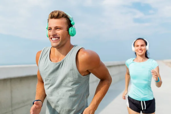 Pareja con auriculares corriendo al aire libre — Foto de Stock