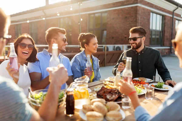 Amis heureux avec des boissons ou bbq partie sur le toit — Photo