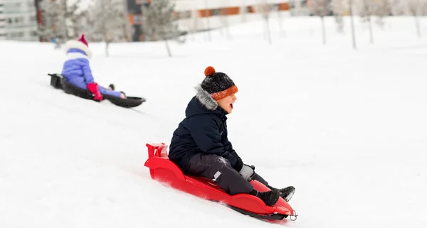 冬にはそりで丘を滑り降りる幸せな子供たち — ストック写真