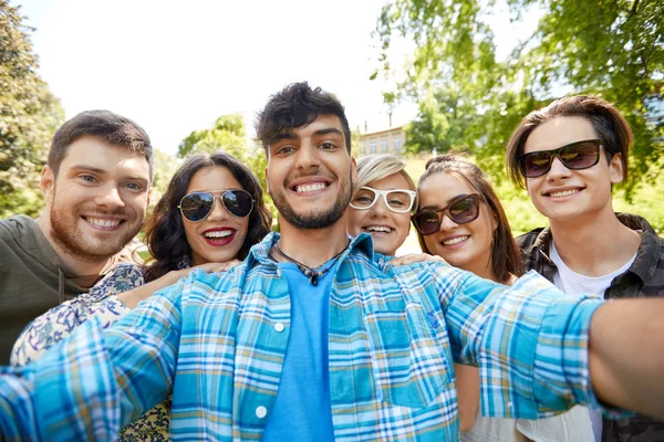 Szczęśliwy uśmiechający się przyjaciółmi, biorąc selfie w lato park — Zdjęcie stockowe