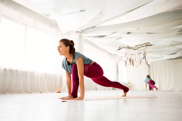 Vrouw het maken van hoge lunge oefening in yoga studio — Stockfoto