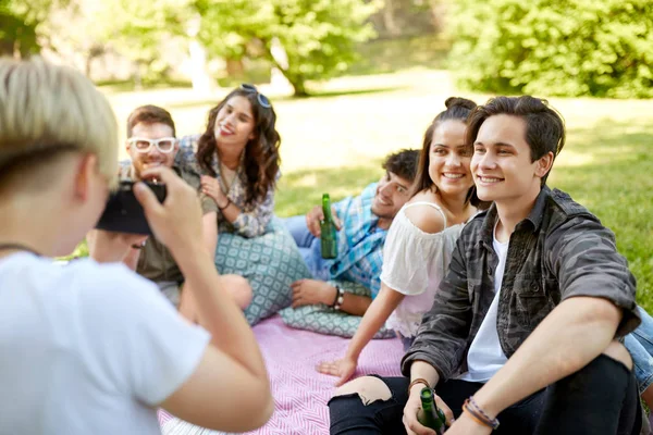 Vänner med drycker som fotograferar på sommar picknick Stockbild