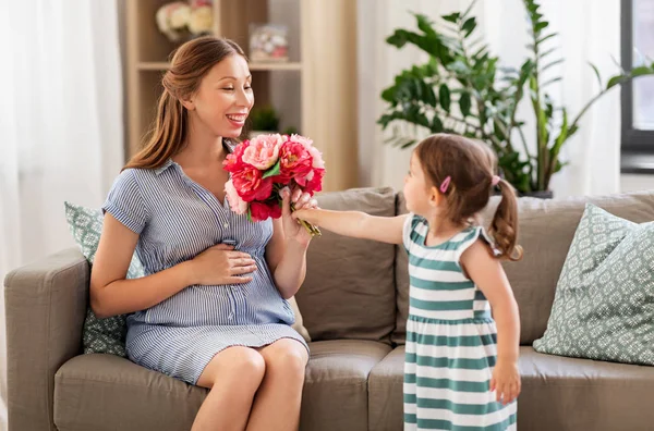 Dziewczyna daje kwiaty do matki w ciąży w domu — Zdjęcie stockowe