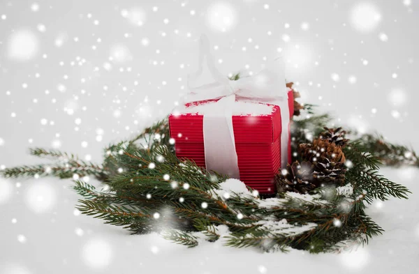 Presente de Natal e grinalda de abeto com cones na neve — Fotografia de Stock