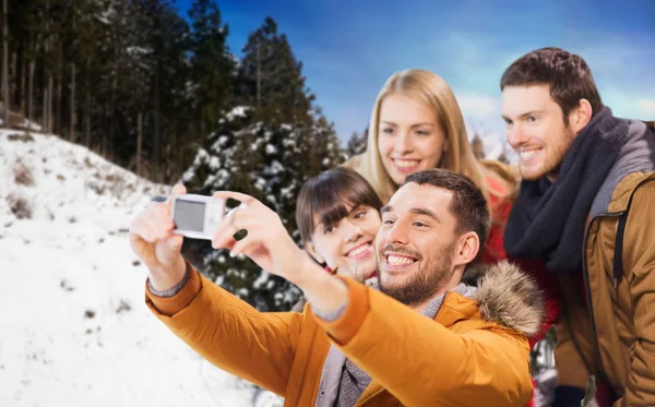 Glada vänner med kameran över vintern bakgrund — Stockfoto