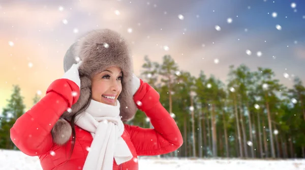 Gelukkig vrouw in bont hoed over winter bos — Stockfoto