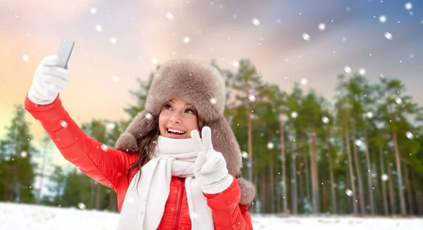 Lycklig kvinna tar selfie över vintern skog — Stockfoto