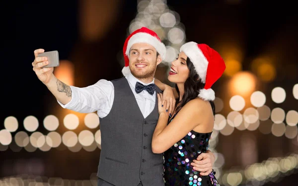 Casal em santa chapéus tomar selfie no Natal — Fotografia de Stock