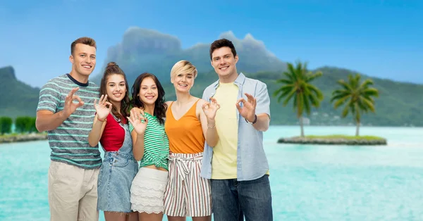 Happy friends showing ok hand sign over bora bora — Stock Photo, Image