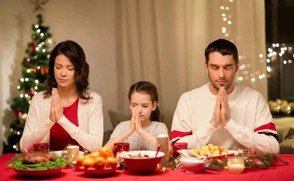 Familie bidden voor de maaltijd bij kerstdiner Stockfoto