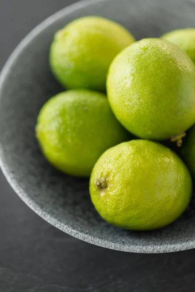 Nahaufnahme ganzer Limetten in Schüssel Stockbild