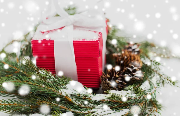 Presente de Natal e grinalda de abeto com cones na neve — Fotografia de Stock